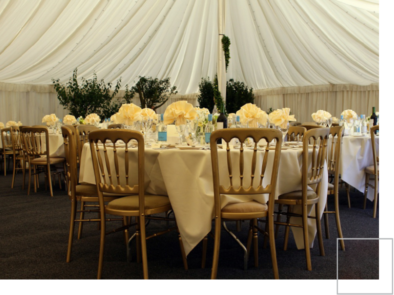 A table set up for an event with white linens and gold chairs.