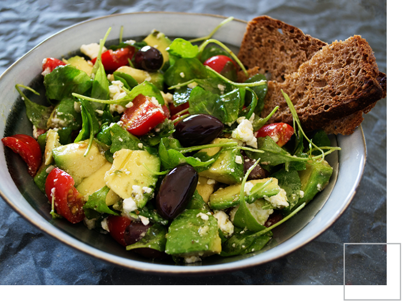 A bowl of salad with bread on the side.