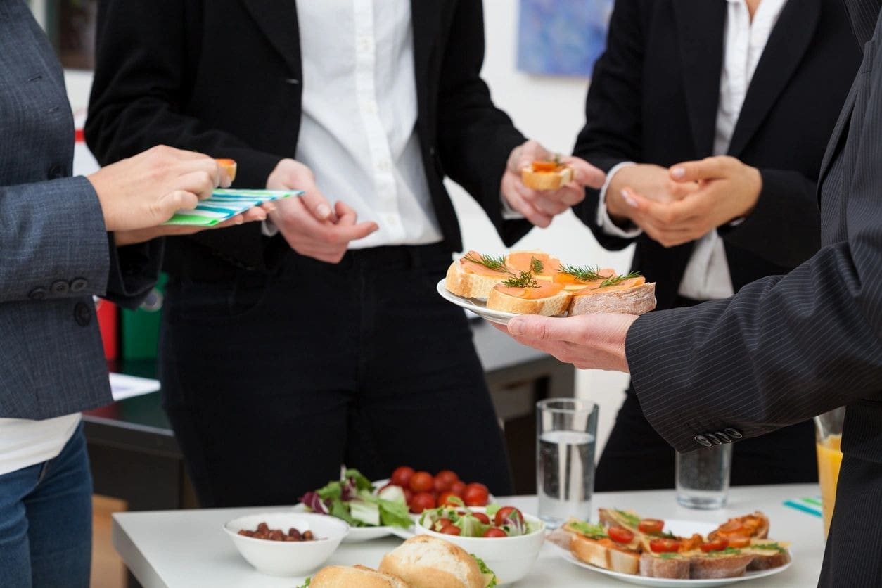 A group of people standing around plates with food.