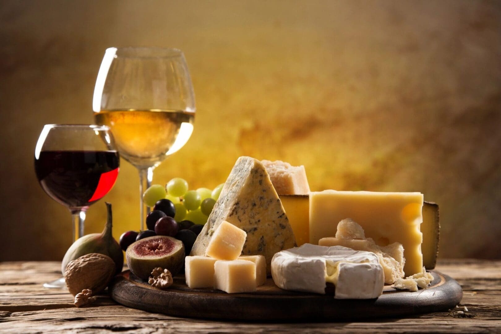 A plate of cheese and wine on the table.